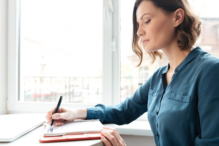 Side view of a woman making notes in her diary