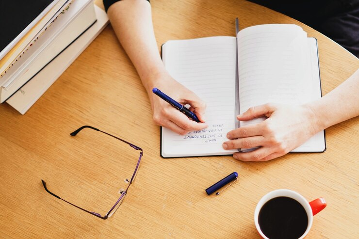 Closeup shot of a woman working or studying from home with a red coffee cup nearby